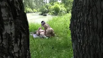 Voyeur outdoors peeps at two naked lesbians. Nudists with big asses sunbathe and enjoy nature and masturbation.