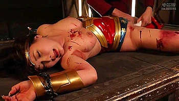 She is restrained and a vibrator is inserted and removed, and then thrust deep into her throat.