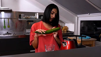 A cute girl peels a cucumber for her older man in a sensual scene.