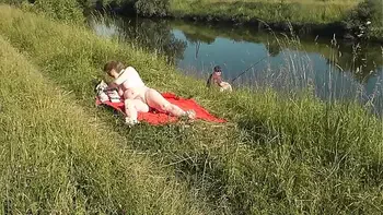 MILF sexy Frina on river bank undressed and sunbathes naked. Random man fisherman watching for her, and in the end decided to join naked woman. Wild beach. Nudist beach. Public nudity. Public exposure. Naked in public